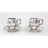 A PAIR OF CHINESE SILVER CUPS AND SAUCERS  each decorated with a figure seated beneath a tree and