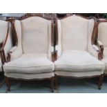 A pair of 20th century cream upholstered wing back open armchairs on cabriole supports, 104cm high x