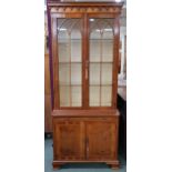 A 20th century reproduction bookcase with moulded cornice over pair of glazed doors on base with