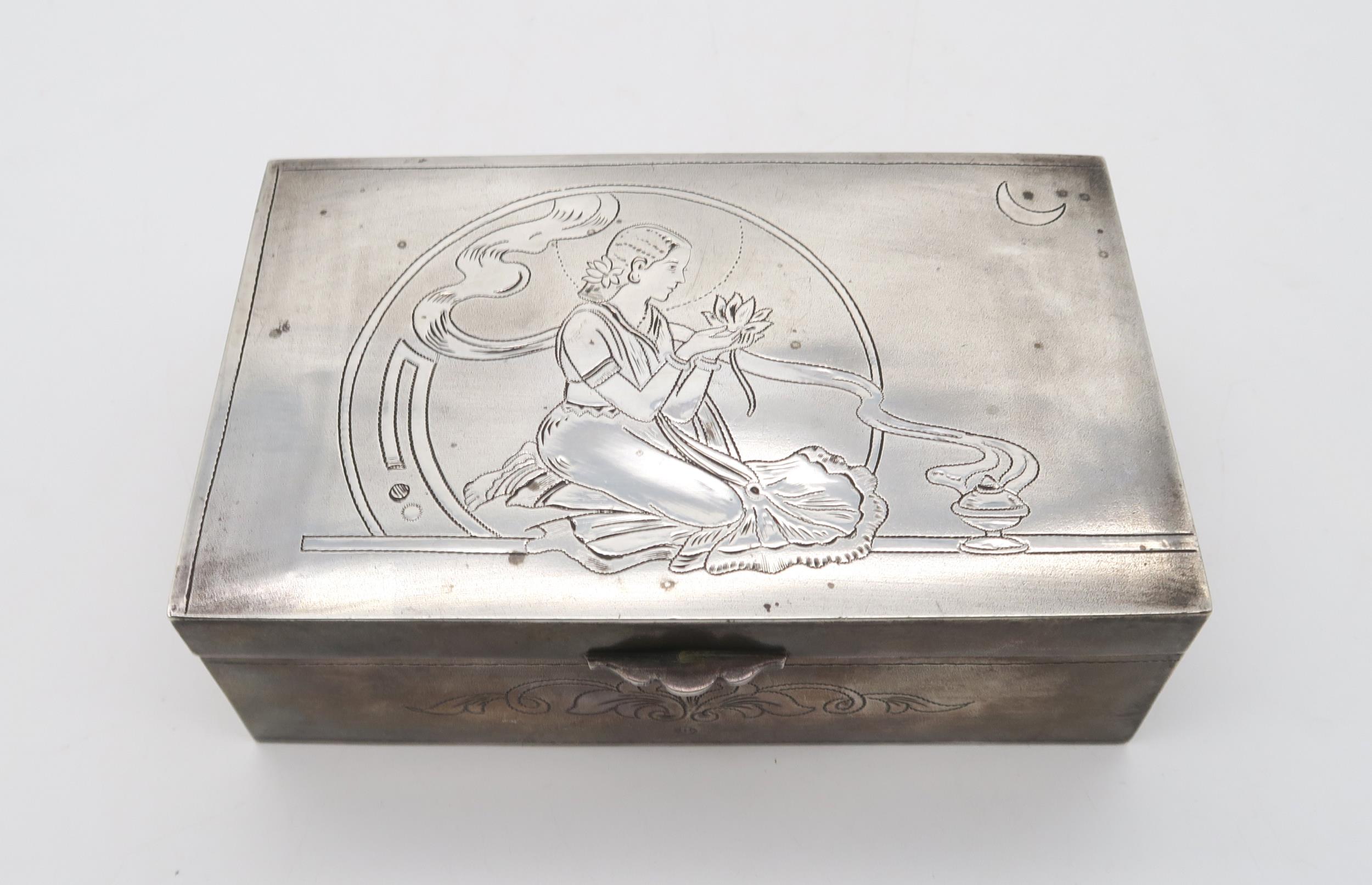 An Indian white metal cigar box, of rectangular form, the lid decorated with a maiden holding a