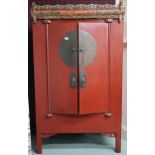 A 20th century red painted Oriental cabinet with carved pierced surmount over pair of cabinets