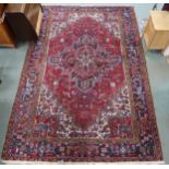 A red geometric patterned ground Belouch rug with dark blue and white geometric central medallion,