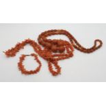 A string of amber coloured beads, largest bead 2.4cm x 1.8cm, weight 63.9gms, together  with a coral