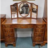 A 20th century reproduction serpentine front dressing table with triple plate dressing mirror over