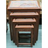 A 20th century Chinese hardwood nest of four tables with each top carved with village scenes, 67cm