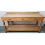 A contemporary pine kitchen work table with three drawers on chamfered square supports joined by