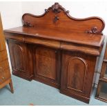 A Victorian mahogany sideboard with carved shaped splashback over three drawers over three