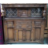 A 20th century beech court style sideboard with inset cabinet door flanked by leaded glass panels