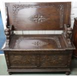 A 20th century oak monks hall bench with hinged top on lion form arms over hinged chest base