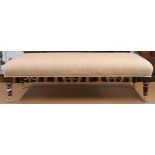 A 20th century Ottoman footstool upholstered in terracotta fabric on turned supports terminating