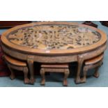An early 20th century Chinese hardwood oval nesting coffee table with carved top depicting village
