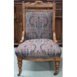A Victorian oak framed nursing chair with damask upholstery on turned supports terminating in