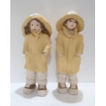 A pair of Austin Production figures of children in raincoats and sou'westers Condition Report:
