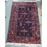 A dark blue ground Balouch rug with geometric central design and multiple multicoloured 209cm long x