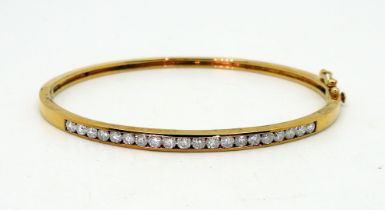 A 9ct gold diamond set bangle, set with estimated approx 1ct of brilliant cut diamonds, inner