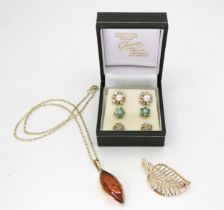 A 9ct gold amber pendant and chain, a leaf shaped brooch, a pair of emerald and diamond flower