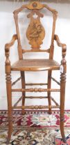 A Victorian walnut framed bergere children's high chair with shaped splat inlaid with game bird over