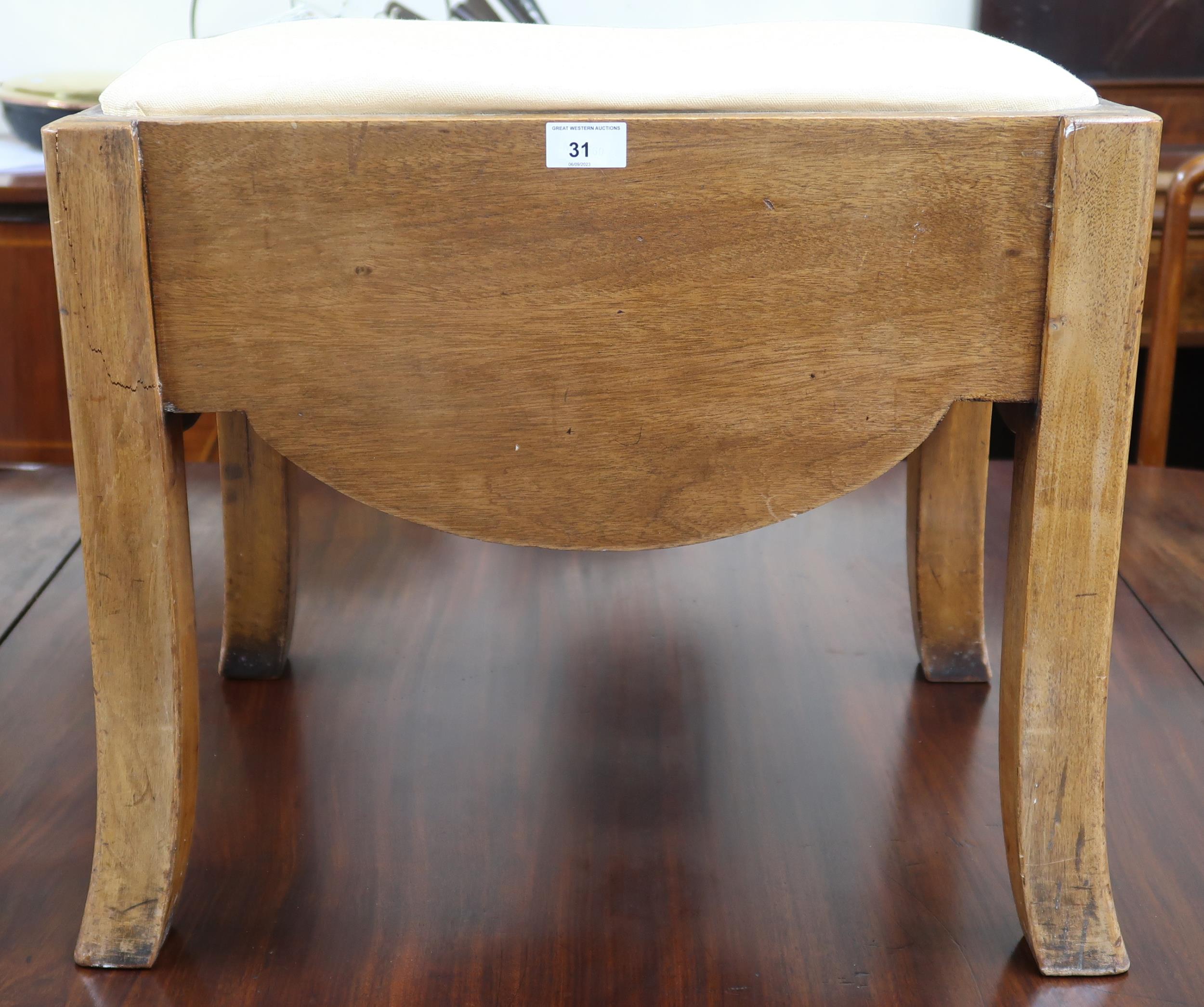 An early 20th century Art Deco style dressing stool with upholstered seat over shaped frieze sides