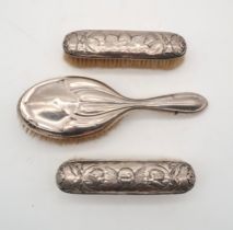 Two silver clothes brushes, decorated with Reynolds Angels, one by William Comyns, London, the other