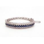 A SAPPHIRE AND DIAMOND BRACELET  in 18k white gold set with twenty one oval sapphires tapering in