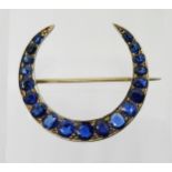 A CRESCENT MOON BROOCH set with sapphires to the galleried mount. Largest sapphire approx 5mm x 4.