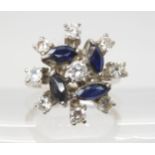 A RETRO SAPPHIRE & DIAMOND CLUSTER RING set throughout in white metal, the four blue marquis cut