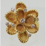 A VINTAGE STATEMENT RING the large multi-petal flower is made in 18ct gold with London hallmarks for