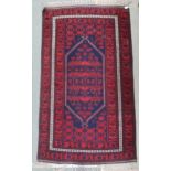A dark blue ground Balouch rug with red geometric central pattern and red geometric border, 198cm