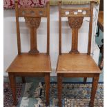 A pair of early 20th century oak Arts and Crafts chairs with carved pierced back rests on square