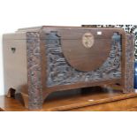 A 20th century Chinese camphorwood blanket chest carved with village scenes, 57cm high x 101cm