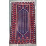 A blue ground Balouch rug with geometric patterned central ground and red and blue geometric border,