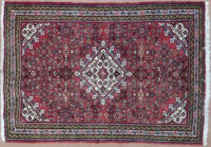 A red ground hamadan rug with cream central medallion, matching spandrels and multiple borders,