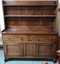 A 20th century oak Wylie & Lochhead kitchen dresser with two tier plate rack over pair of drawers