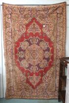 A red ground Tabriz style wall tapestry with multicoloured central medallion, beige spandrels and