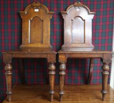 A pair of 19th century stained oak court chairs with carved shaped splats over plain seats on turned