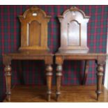 A pair of 19th century stained oak court chairs with carved shaped splats over plain seats on turned