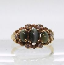 A yellow metal ring set with three cats eye chrysoberyl and diamond accents, finger size O1/2,