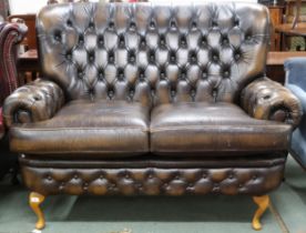 A 20th century brown leather button back Chesterfield style two seater settee on cabriole