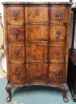 An early 20th century walnut veneered serpentine front four drawer chest on Queen Anne supports,