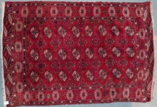 A red ground Bokhara rug with all-over lozenge design and multicoloured geometric lozenge border,