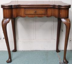 An Edwardian mahogany fold over bridge table with shaped top concealing baize play surface on