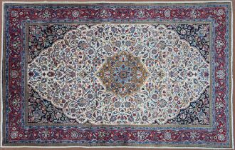 A CREAM GROUND KASHAN RUG  with yellow and blue central medallion and dark blue spandrels on a