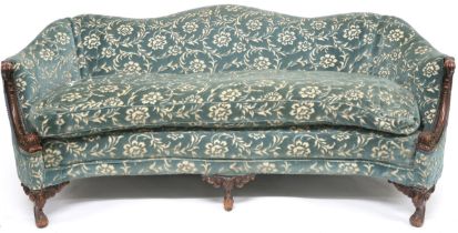 A VICTORIAN WALNUT FRAMED HUMPBACK SETTEE  with floral upholstery, scrolled acanthus carved arms