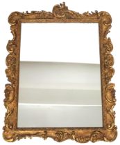 A 19TH CENTURY GILT FRAMED ROCOCCO WALL MIRROR  with rectangular mirror pane within scrolled