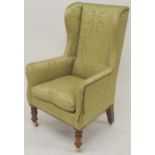 A VICTORIAN GREEN DAMASK UPHOLTERED WINGBACK ARMCHAIR  with high winged back on turned front