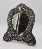 AN EDWARDIAN SILVER FRAMED HEART-SHAPED EASEL BACK MIRROR by Henry Matthews, Birmingham 1904, the