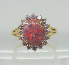 AN OPAL & DIAMOND RING set with an 11mm x 9mm x 1.9mm mainly red blue opal, surrounded with  halo of