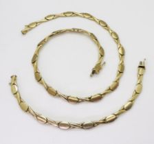 A 9CT GOLD SUITE comprising of a necklace and matching bracelet, with brushed oval and shiny kiss