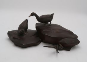 A JAPANESE BRONZE MODEL OF TWO DUCKS standing on rockwork, 17cm high and 39cm wide Condition