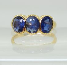 A three stone sapphire ring, mounted in bright yellow metal, in pretty cut back bezel settings,